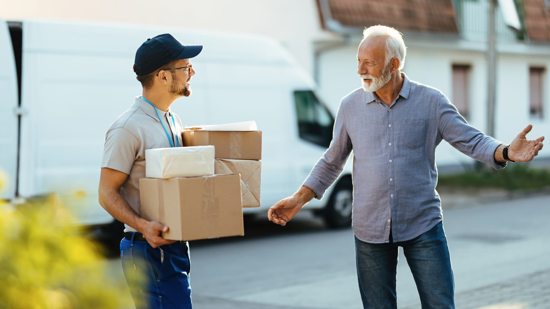 Happy senior man welcoming courier who is delivering him moving boxes at home
